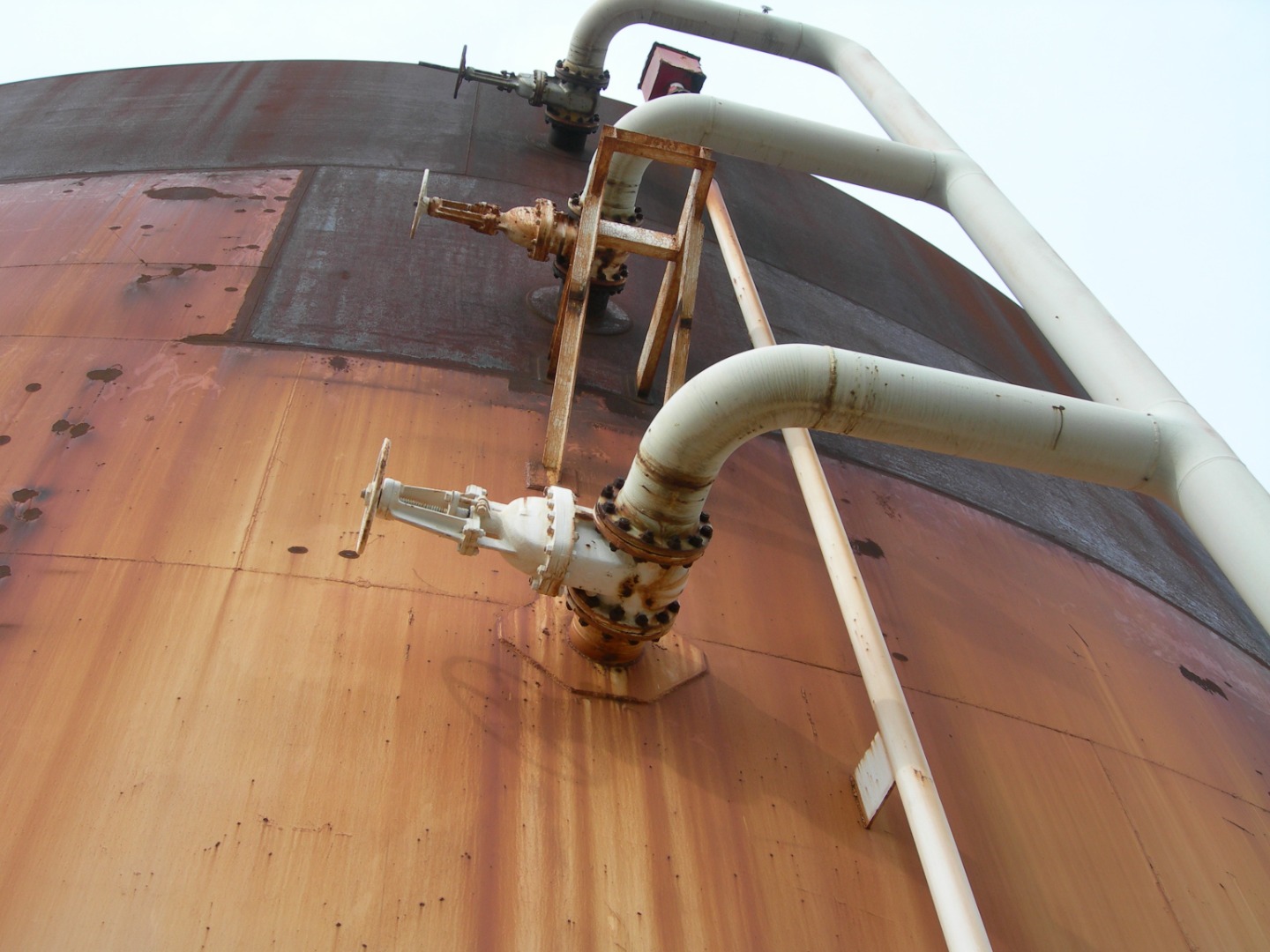 Significant rust is evident across the surface of a steel chemical storage tank.