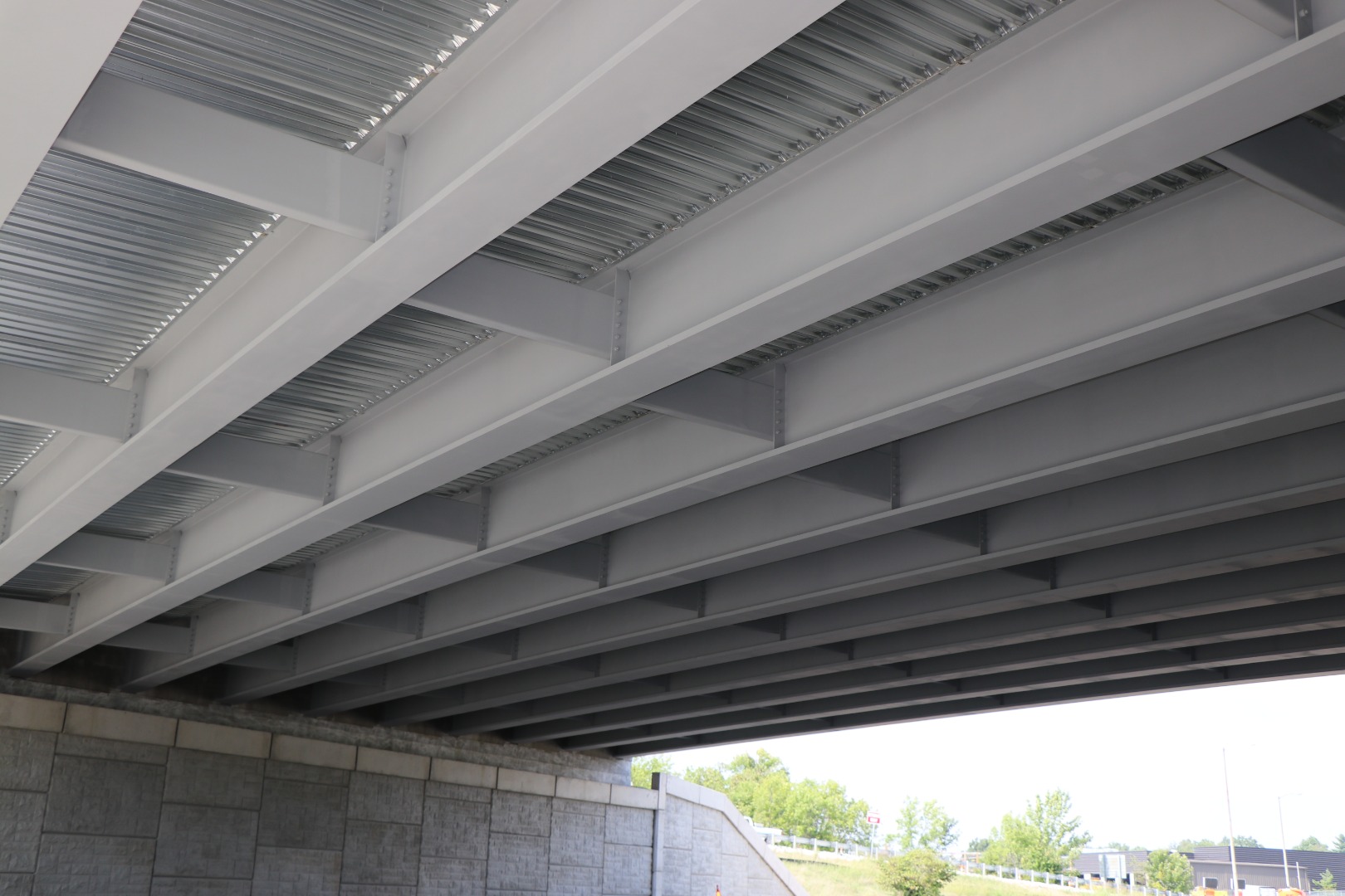 The underside of a highway overpass showing gray painted structural steel beams.