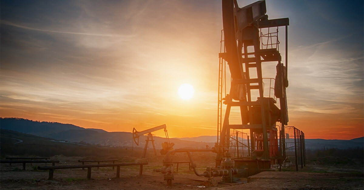 Oil rigs pump oil from the ground in the hot sun. 