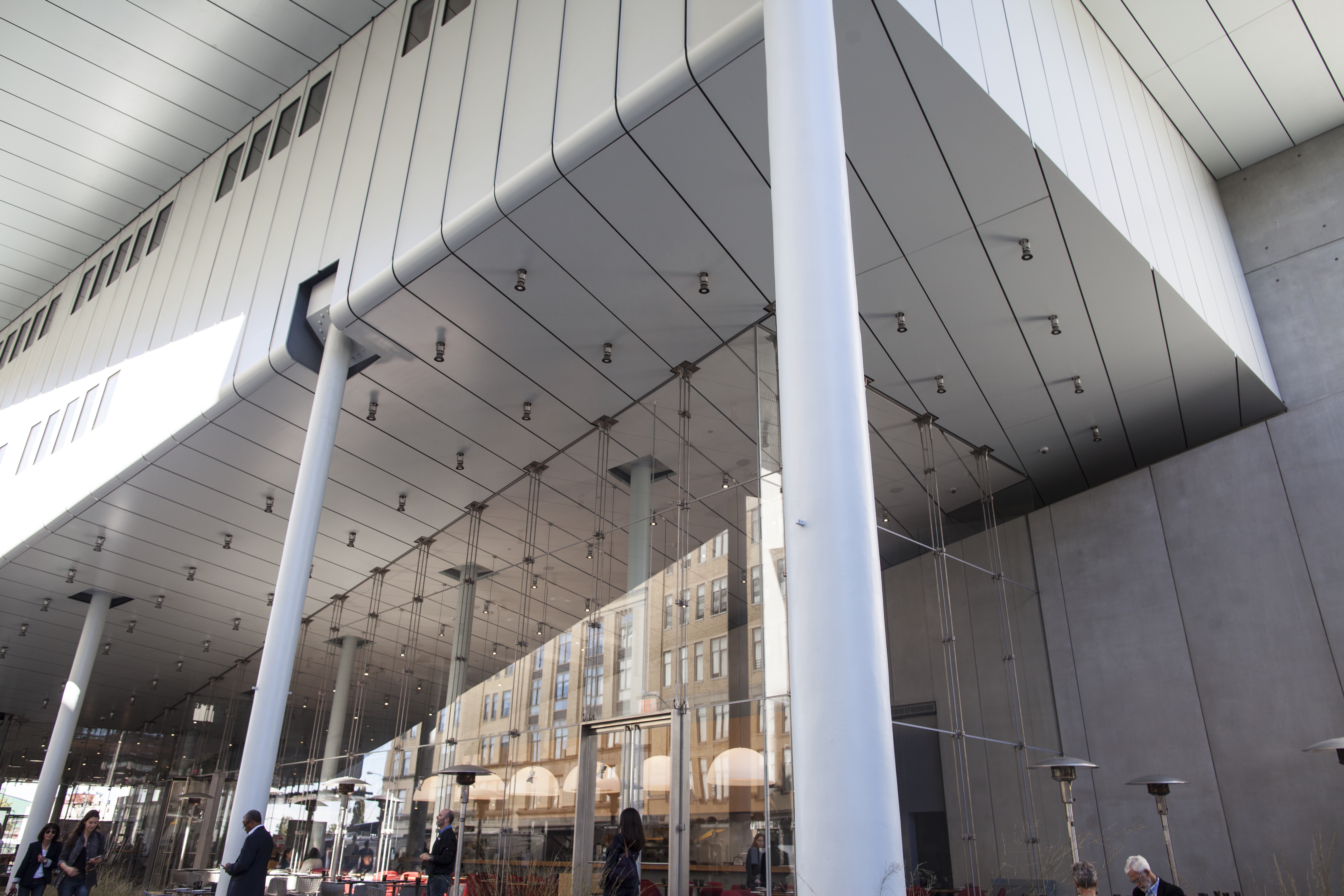 A modern commercial building with white circular support columns and a reflective glass exterior.