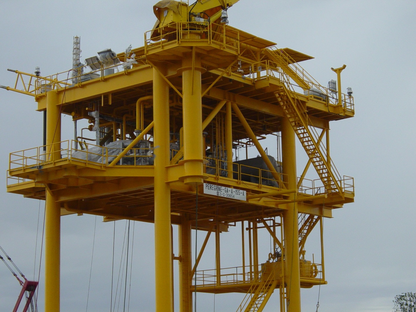 An offshore oil derrick with bright yellow structural steel and containing process equipment.